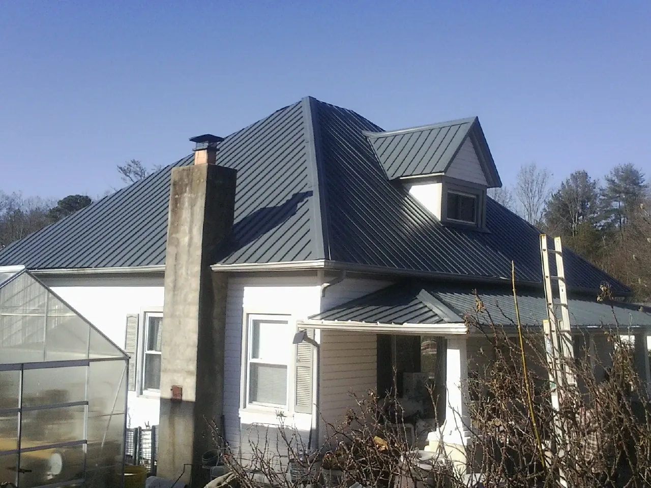 Dark blue standing seam metal roof on a white farmhouse with dormer — Slate & Tile Roof Repair by Roofing Brothers in Mogadore