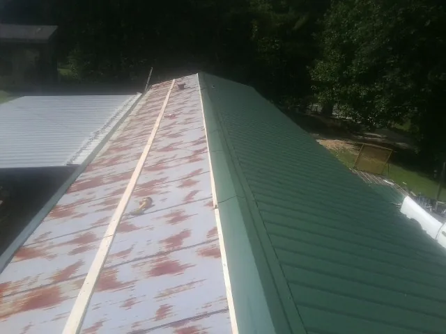 Old rusted panels beside newly installed green metal roofing — Wind Damage Roof Repair by Roofing Brothers in Mogadore