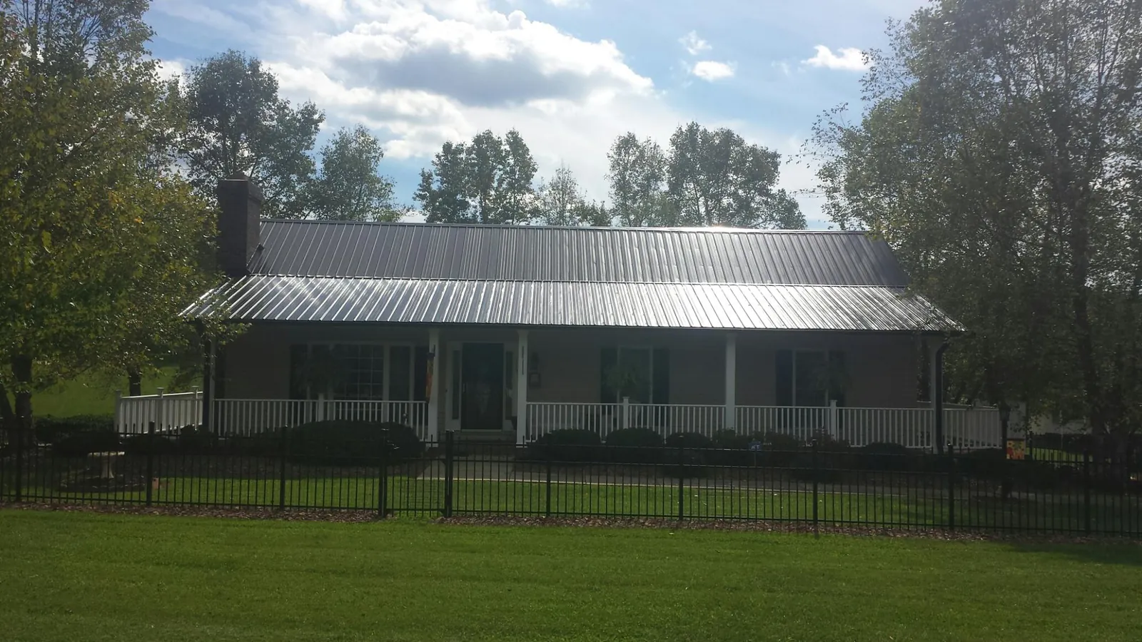 Gray metal roof on a brick ranch with a full width front porch — Gutter Guard Installation work by our crew in Mogadore