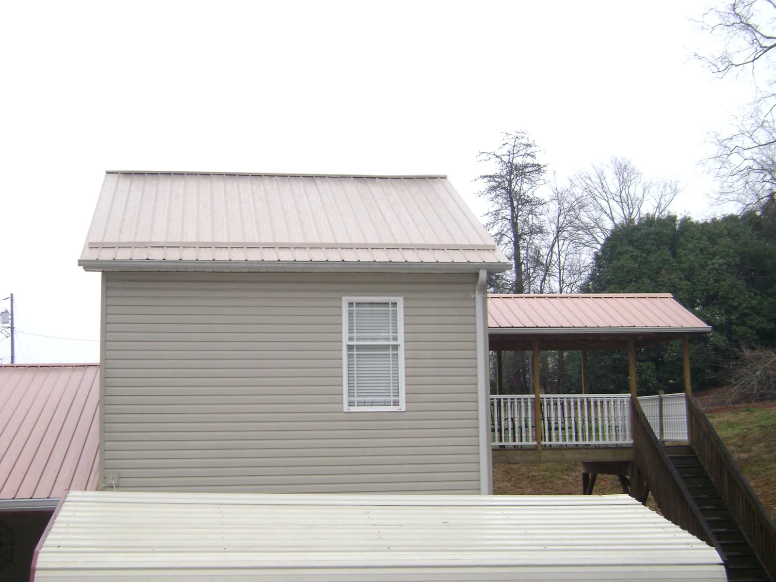 Tan metal roofs on a two story addition and attached porch, from a Roof Replacement job in Mogadore