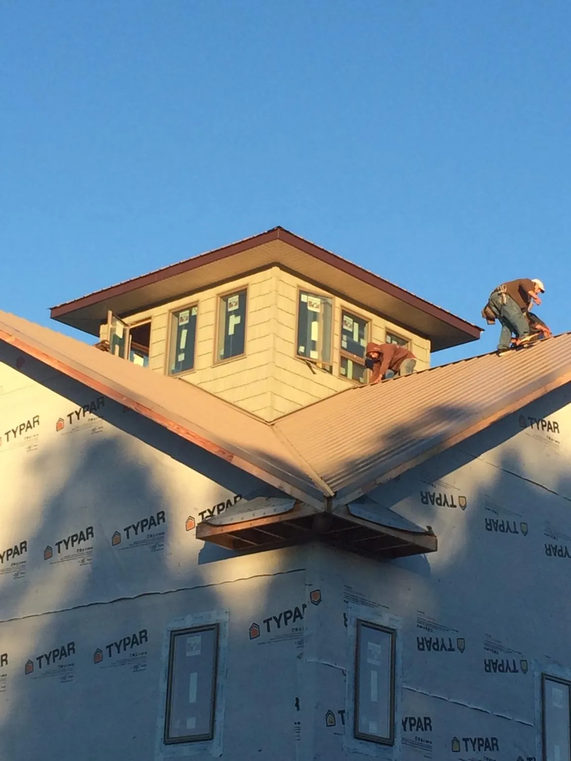 Roofers working around a rooftop cupola on a new metal roof at sunset — Roof Waterproofing in Mogadore by Roofing Brothers